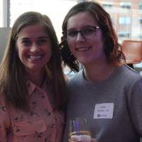 Two alumnae smile for a photo together while enjoying their drinks